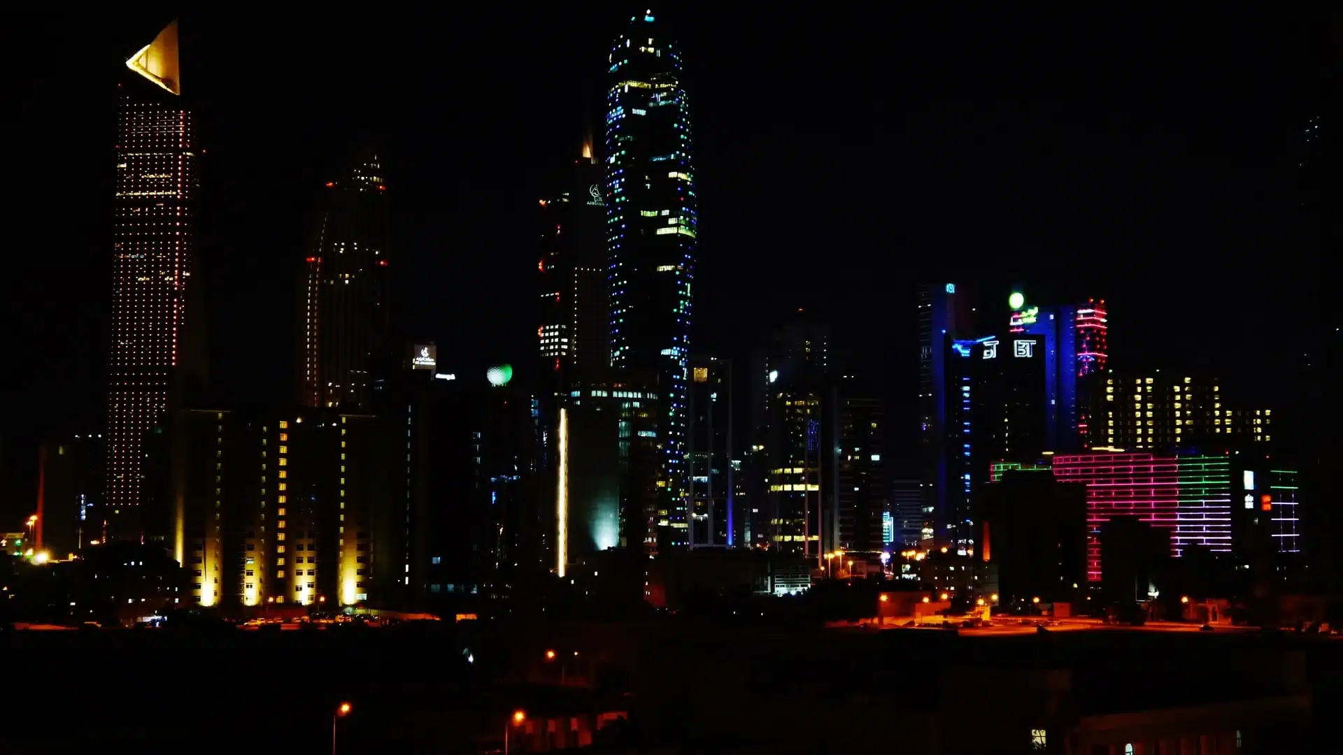 De skyline van Kuwait City bij nacht met verlichte wolkenkrabbers.