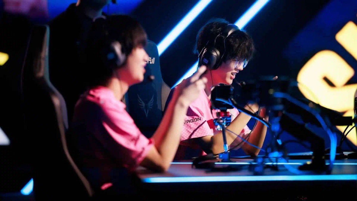Twee professionele esports-spelers in roze shirts met headsets op een wedstrijd podium.