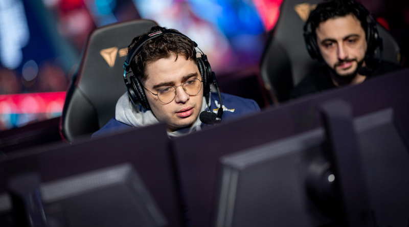 Två personer med headset sitter framför datorskärmar i en esportmiljö.