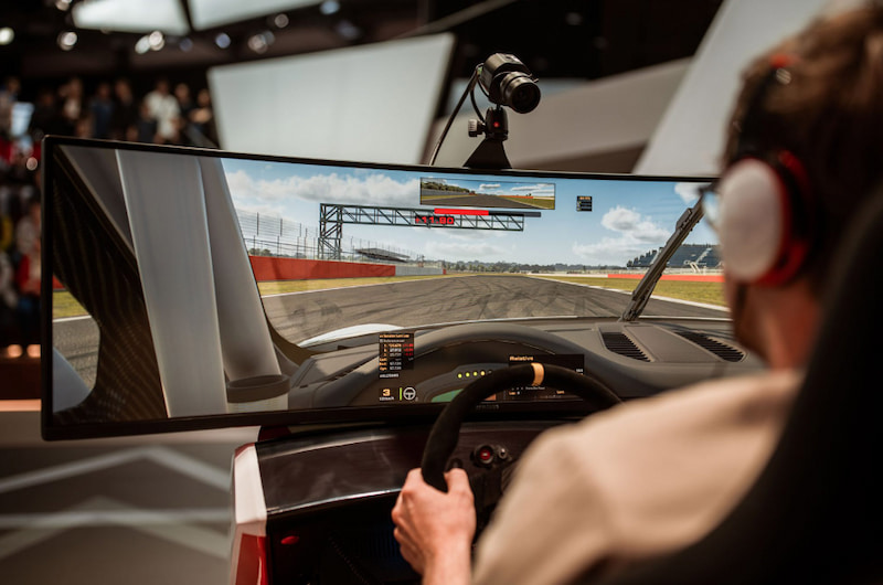 En person kör iRacing på en racingsimulator med ratt och skärm, headset på, i en realistisk virtuell racingmiljö.