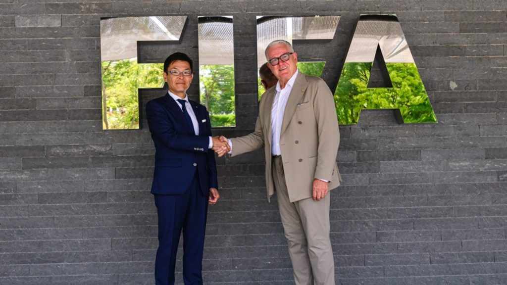 Image of KONAMI and FIFA representatives standing in front of FIFA sign on a building