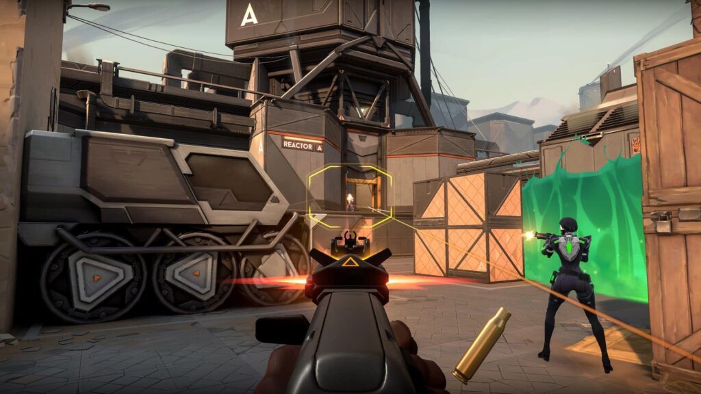 A player aims a gun at an enemy through a targeting reticle, while a teammate stands ready behind a barrier in a VALORANT game scene.