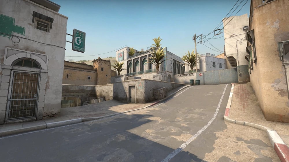 A Long on the Dust 2 map in Counter-Strike: Global Offensive, showing the uphill road toward A Site, Middle Eastern buildings, palm trees, and directional signs on the walls.
