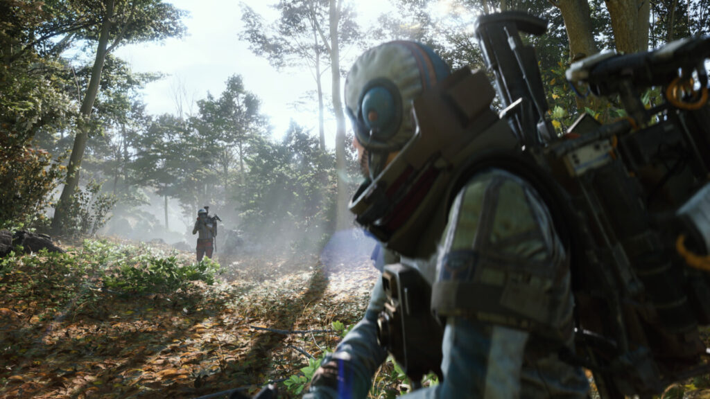 Two characters in futuristic gear move cautiously through a sunlit forest, with one figure in focus and another approaching in the background — from Arc Raiders.