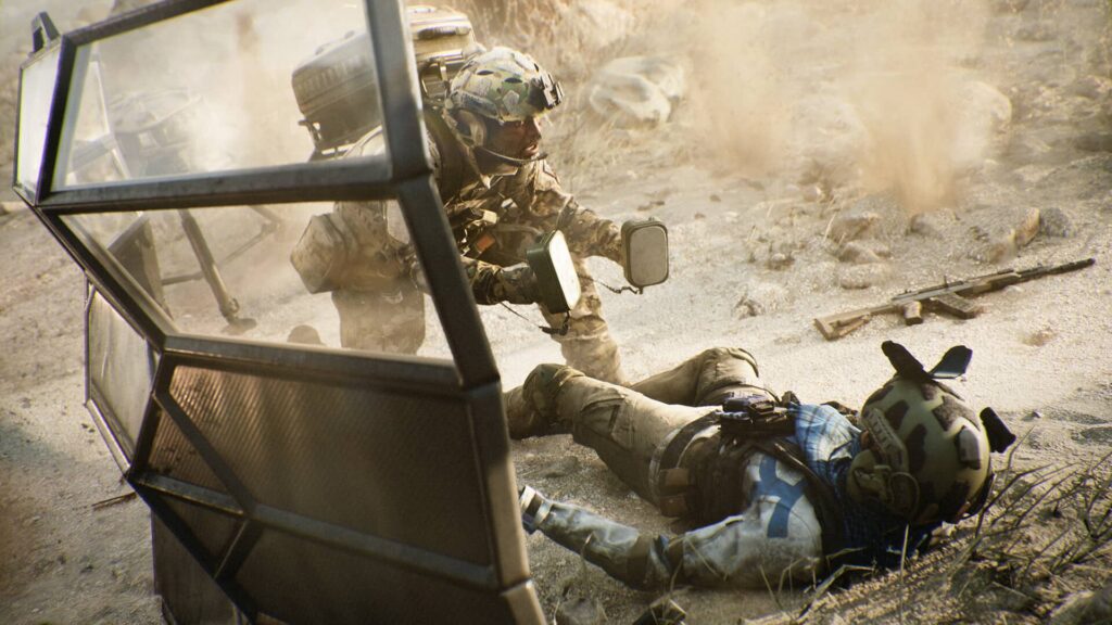 A soldier in Battlefield 6 uses defibrillators to revive a fallen comrade on a dusty battlefield, with debris and gunfire in the background.