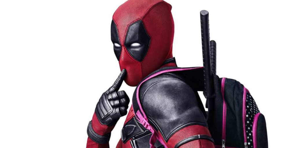 Deadpool in his red and black suit poses with a finger to his lips, wearing a backpack and katanas on his back, striking a playful and mischievous look.