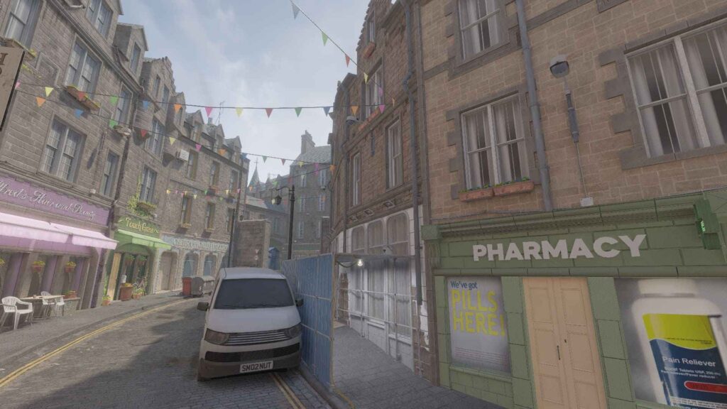 A quaint street scene with stone buildings, colorful bunting, a pharmacy, and a van parked amidst shops and outdoor seating.