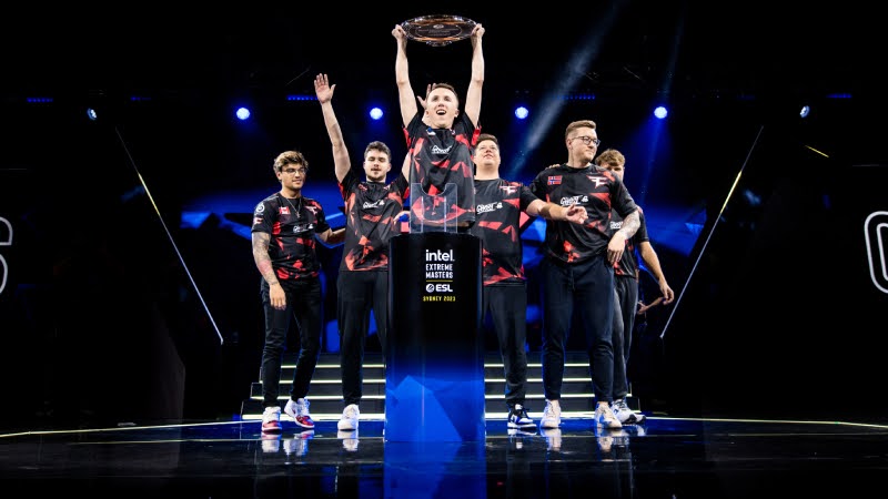 FaZe Clan players celebrating on stage after winning the first Tier-1 Counter-Strike 2 tournament at IEM Sydney 2023, with one player holding the trophy above his head while the team gathers around the podium.