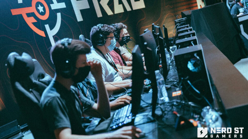 A row of focused gamers in headsets, sitting at computers with a vibrant esports backdrop featuring the word "PRIZE."