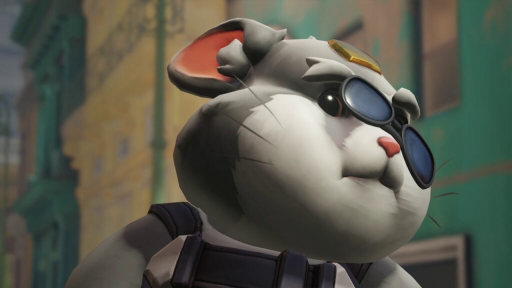 Close-up of Wrecking Ball (Hammond) in his High Roller skin from Overwatch 2, styled as a white plush toy hamster wearing black goggles and a golden accessory, set against a blurred urban background.