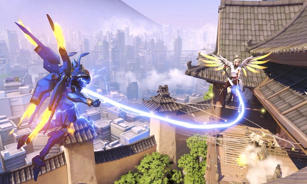 Mercy boosts Pharah’s damage with her staff in Overwatch 2, mid-air above a cityscape.