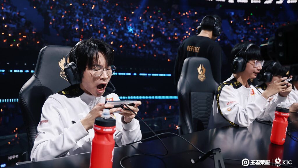 Mobile esports players intensely focused on a match, playing on smartphones with headsets, during a live tournament in a packed arena.