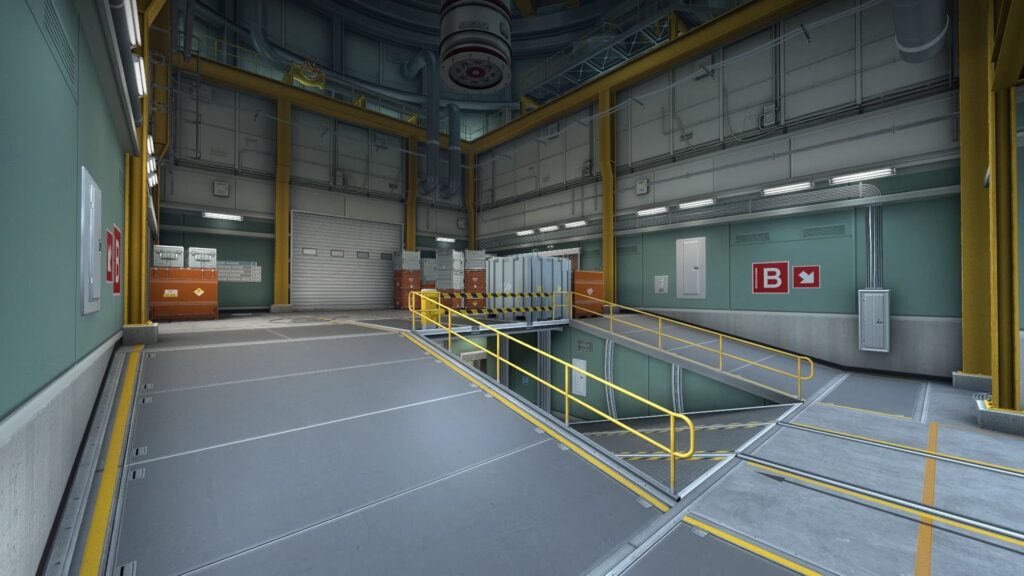 Interior of the B bombsite ramp room on the Nuke map in Counter-Strike, showing a clean, industrial space with metal railings, yellow beams, and labeled doors, including a red "B" site marker on the wall.