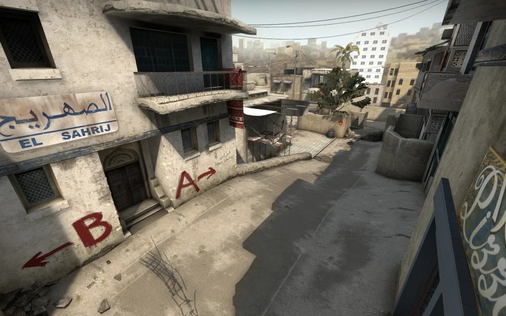 Dust 2 alley in Counter-Strike: Global Offensive with graffiti pointing to A and B sites, Middle Eastern buildings, and overhead wires.