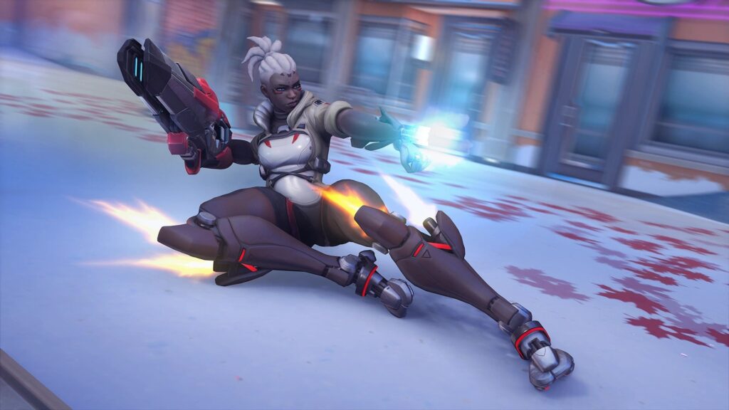 Sojourn from Overwatch 2 sliding across an icy surface while aiming her weapon, with jet boosters active on her legs and energy glowing from her hand, in a dynamic in-game action scene.