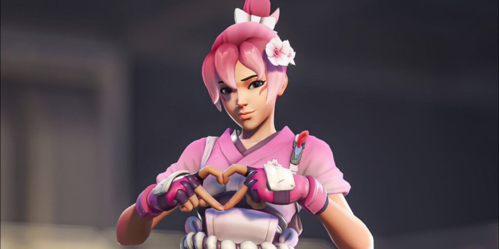 A hero from Overwatch dressed in pink attire forming a heart shape with her hands, adorned with flowers in her hair, exuding a cheerful vibe.