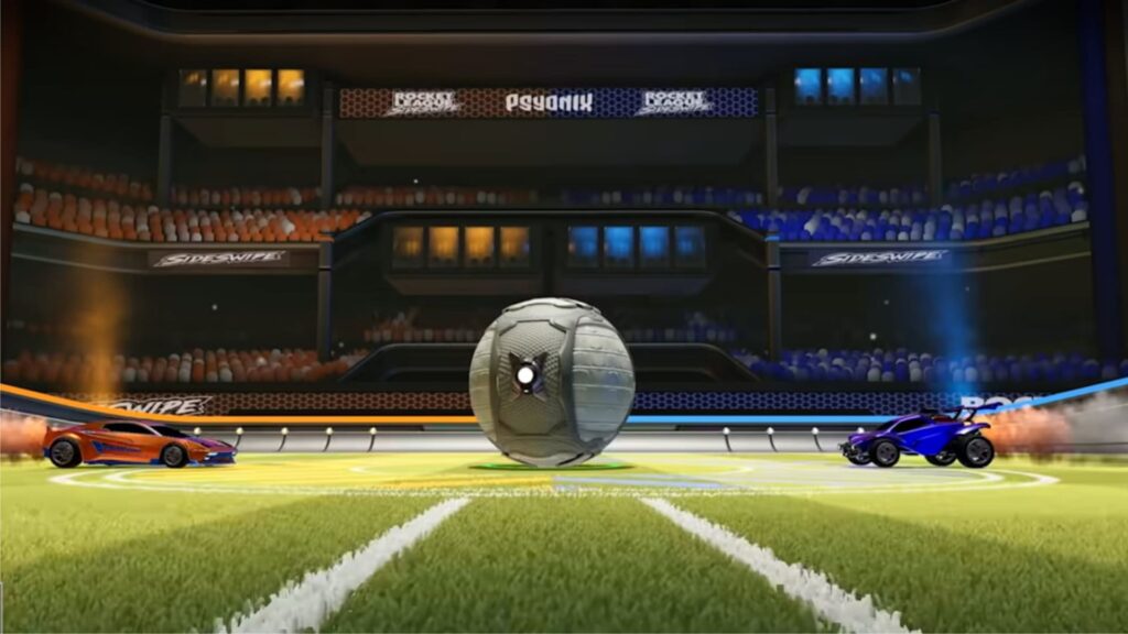 Two colorful cars, orange and blue, are poised on a grassy soccer field, facing a large, central ball in a competitive gaming setting.