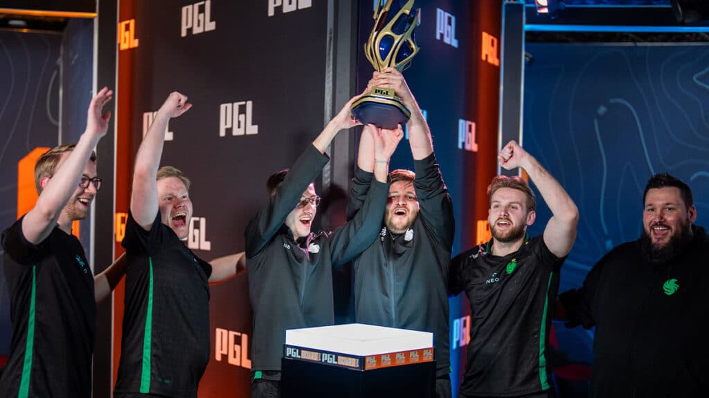 Team Falcons players celebrate their victory at PGL Bucharest by lifting the championship trophy on stage.