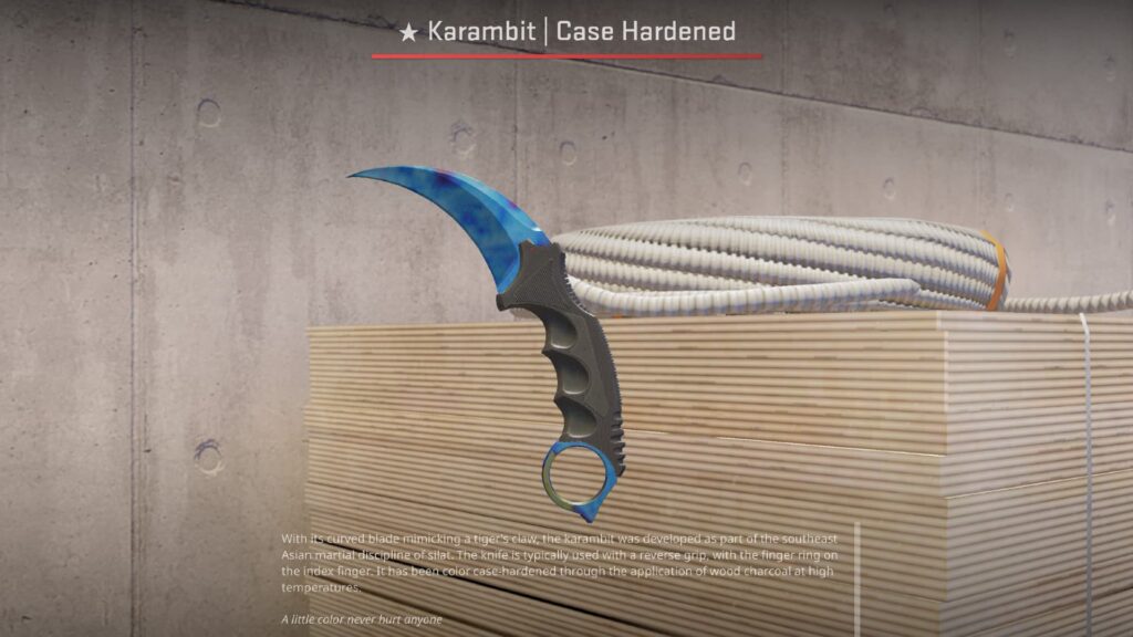 Karambit | Case Hardened with a bright blue blade displayed on stacked wood panels in a CS2 environment.