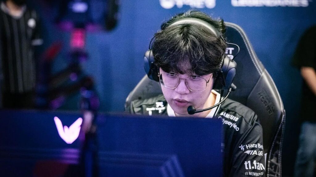 Zeus focused during a professional League of Legends match, wearing a headset and T1 team jersey while playing on stage.