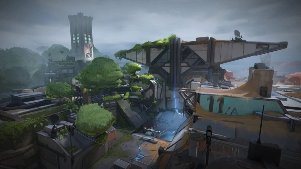 A futuristic landscape of a Fracture map of VALORANT featuring overgrown buildings, a tall tower, and satellite dishes under a cloudy sky, evoking a post-apocalyptic theme.