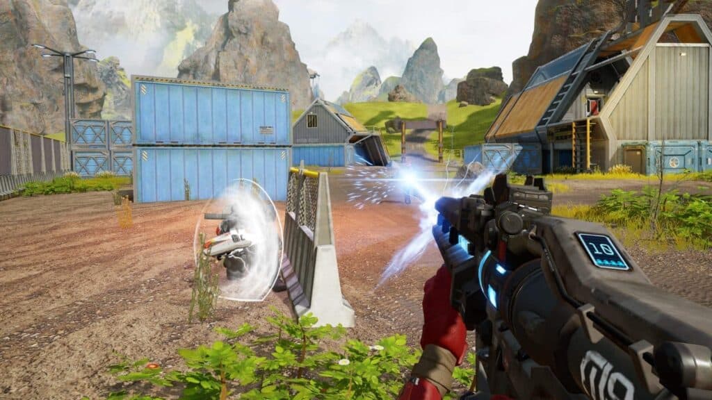 A player fires a futuristic weapon towards a robotic target in a gaming arena from Apex Legends Mobile with mountains in the background.