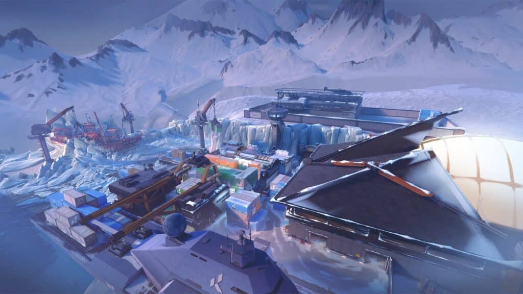 Aerial view of a snowy industrial complex of an Icebox map of VALORANT with cranes, cargo containers, and an icy landscape surrounded by mountains.