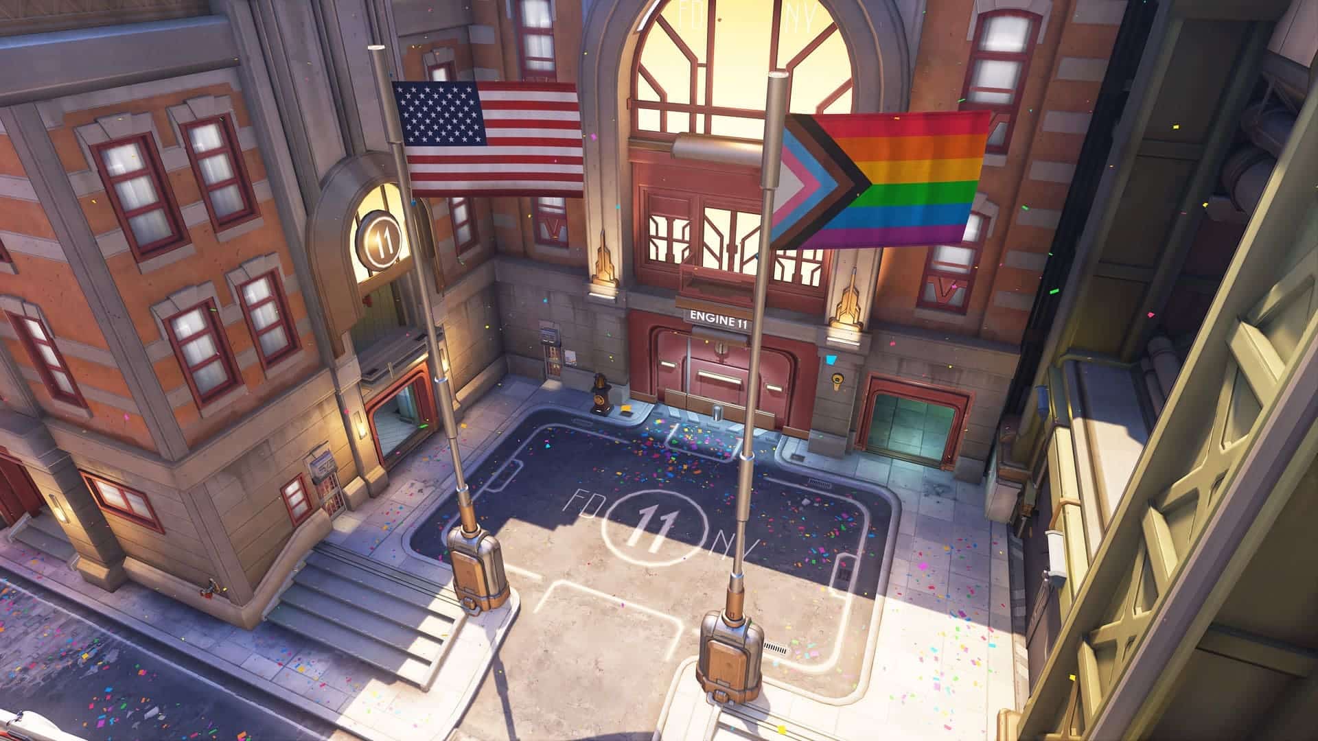 The American flag and a rainbow pride flag wave outside Fire Station 11, resembling a hero outpost, amidst vibrant confetti in a lively urban scene — a celebration of unity and diversity in the world of Overwatch 2.
