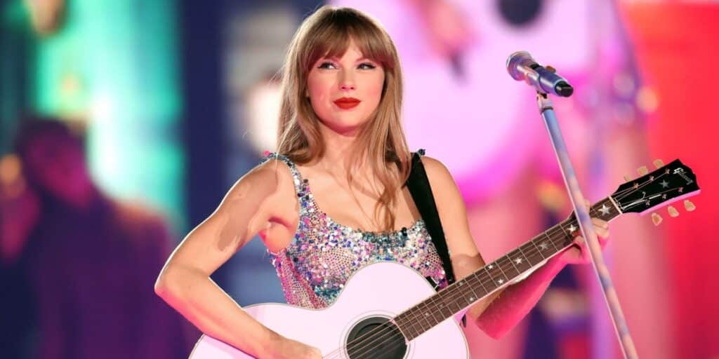 Taylor Swift plays a white acoustic guitar on stage