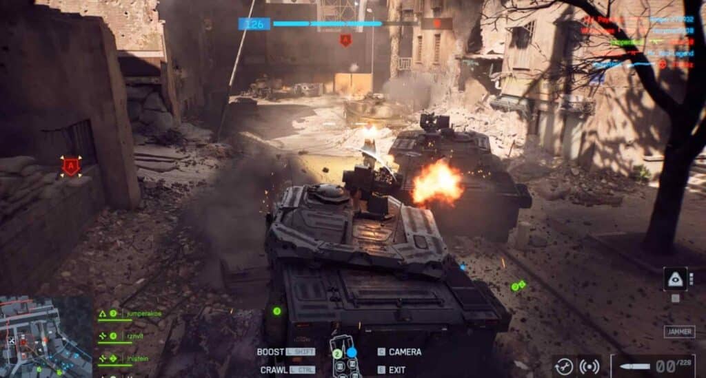 Two armored tanks engage in battle on a destroyed urban street, with explosions and debris surrounding them. Game interface visible.