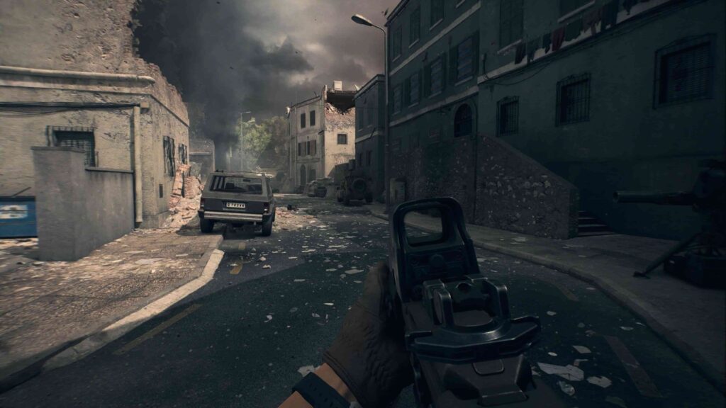 First-person view down a war-torn urban street. A soldier's gloved hand holds a rifle