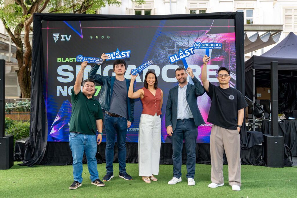 Image of BLAST and Singapore Tourism Board representatitves holding signs while standing in front of a screen projecting information about BLAST Slam IV