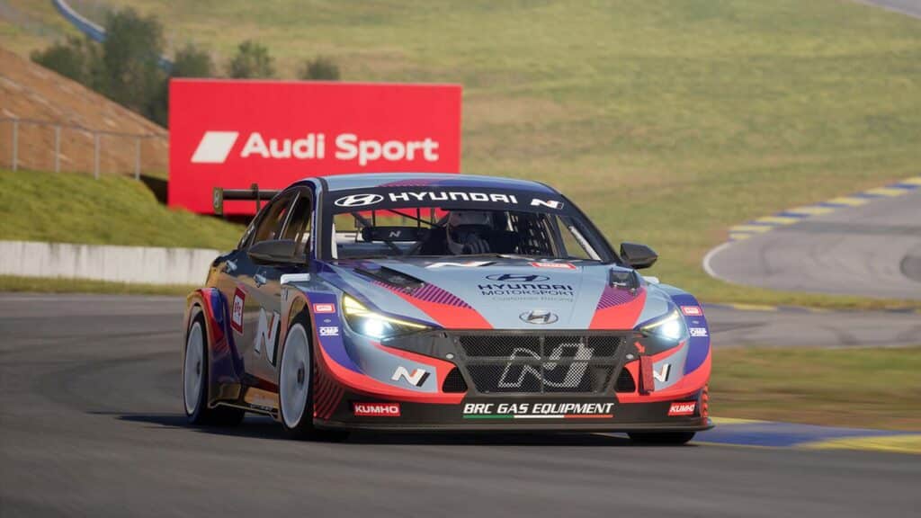Image of Rennsport Hyundai TCR race car driving around Road Atlanta. A red Audi Sport sign is in the background