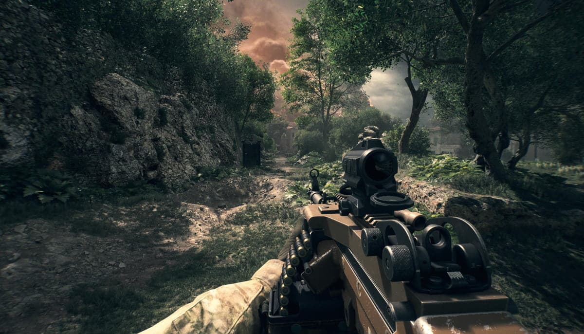 First-person view of a soldier holding a rifle in a lush, rocky forest setting