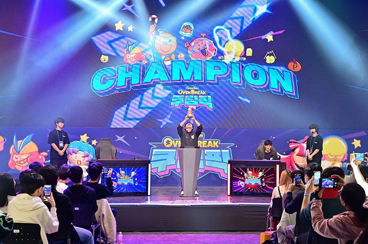 CookieRun OvenBreak champion revealed on stage, holding a trophy