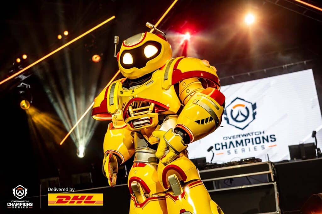 Image of red and yellow robod standing in front of screen displaying OWCS logo