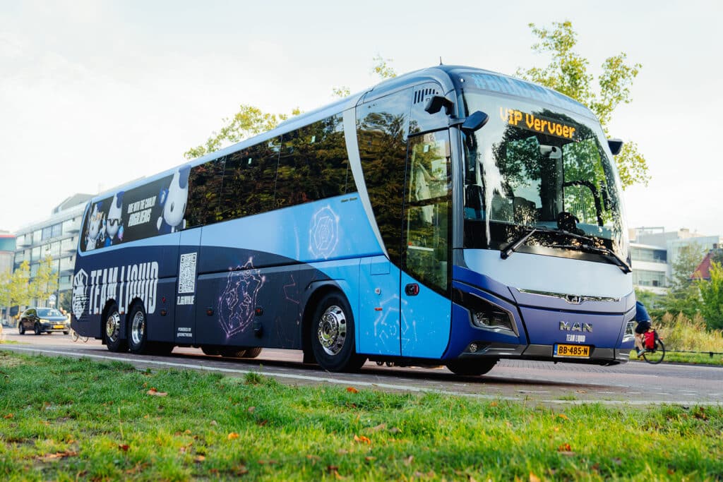 Immagine di un autobus blu del marchio liquido puntato su una strada. Una patch di erba è in primo piano