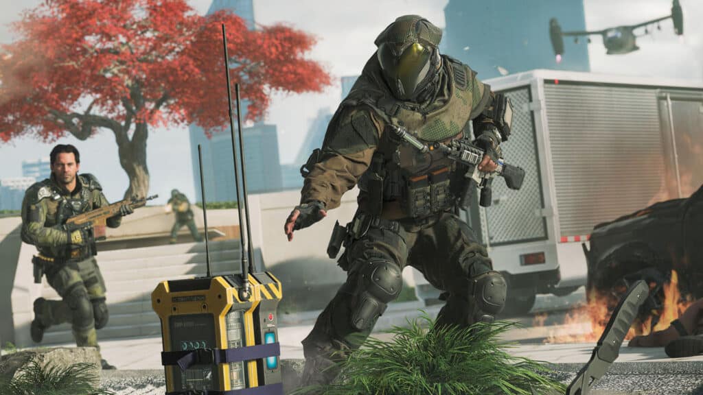 Image of Black Ops 7 player reaching out to touch yellow device while holding weapon in other hand. A teammate holding a rifle is in the background