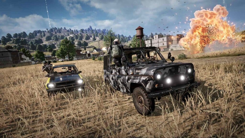 Captura de tela do jogo PUBG com explosão e veículos militares atravessando um campo gramado