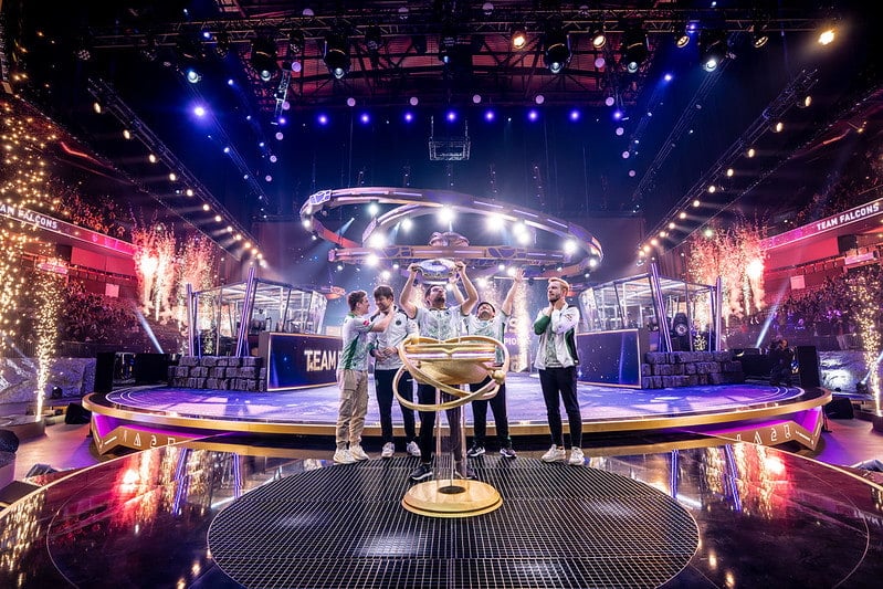 A Dota 2 team celebrates on stage while lifting the tournament trophy