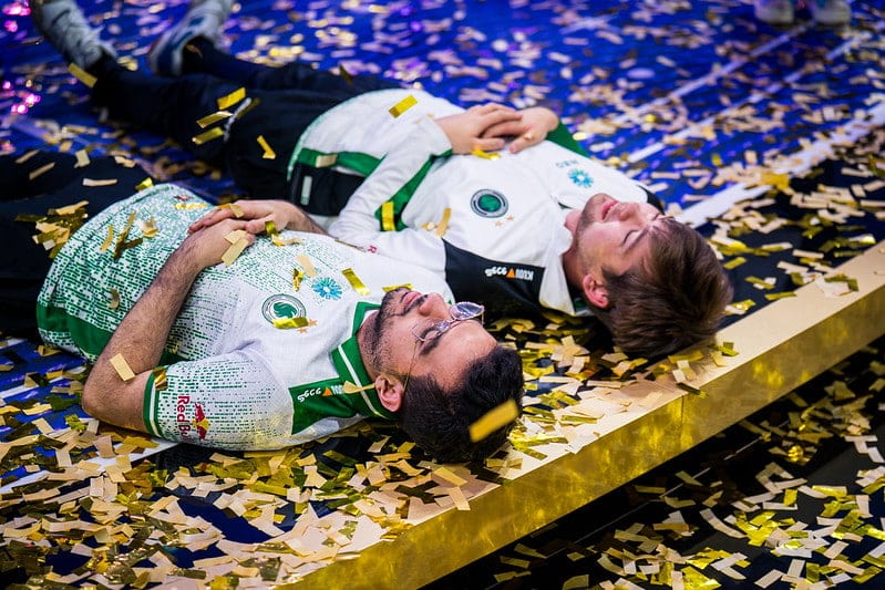 Malr1ne and ATF lie on a stage covered in golden confetti