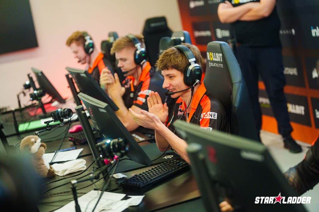 Bild des Fnatic Counter-Strike-Teams, das beim StarLadder Budapest Major antritt. Der Spieler klatscht in die Hände und lächelt dabei auf einen Gaming-Monitor