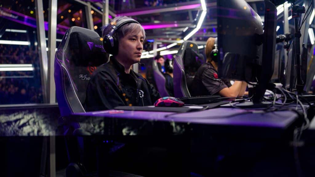 Professional Dota 2 player Wang "Ame" Chunyu from the team Xtreme Gaming, with purple-dyed hair, sits at a computer wearing a headset during a tournament match