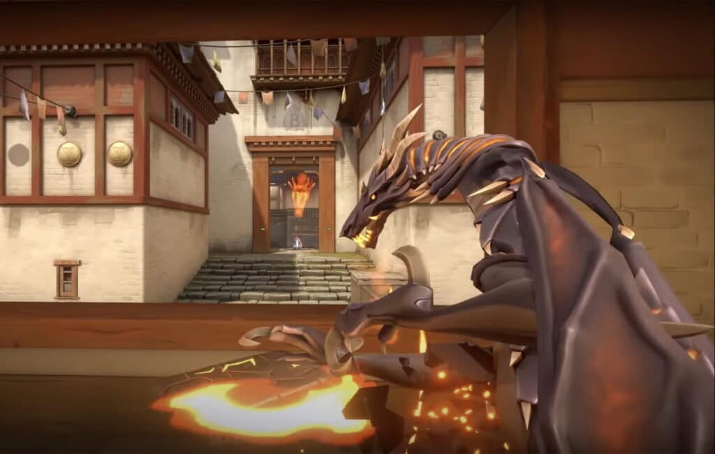 
An in-game screenshot from the tactical shooter Valorant shows a first-person perspective holding a weapon with the animated "Elderflame" dragon skin