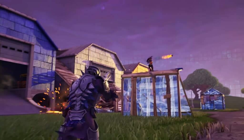 A screenshot from the video game Fortnite, showing a character in blue armor aiming at an enemy standing on a wooden structure in a farm setting