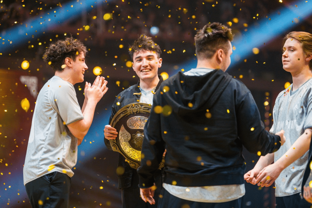 The image shows Team Spirit players celebrating after lifting the Aegis of Champions at The International 2026 in Shanghai.